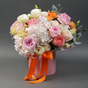 Composition of peony-shaped roses with hydrangeas in a hat box
